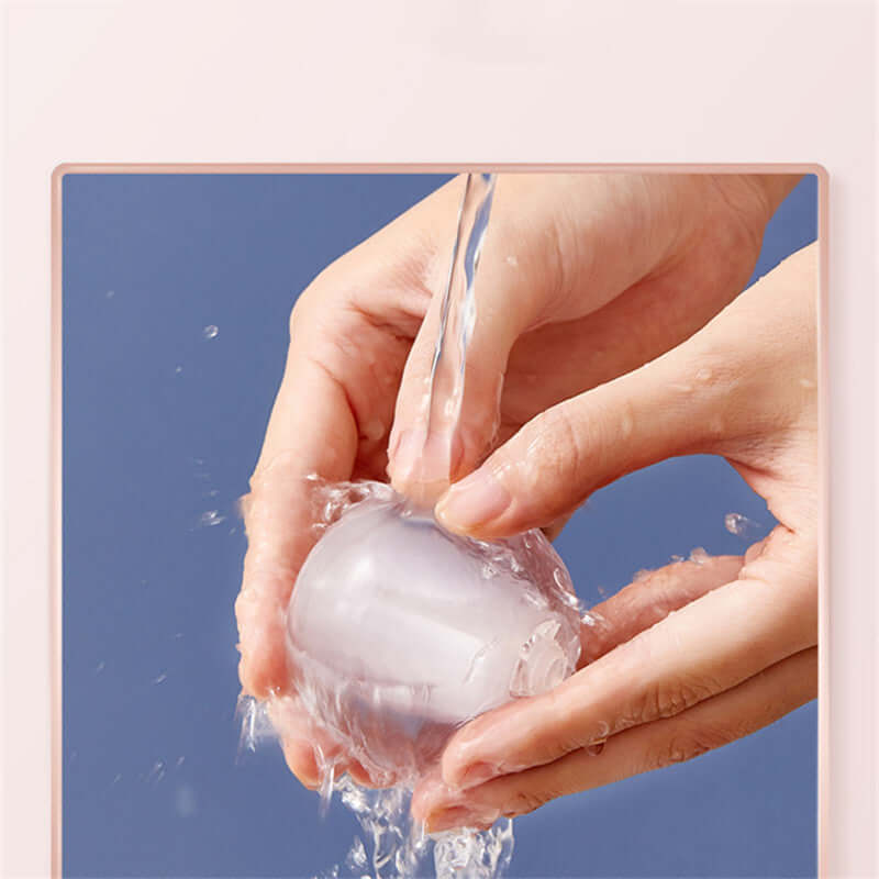 A person washing a ball-shaped reusable lint roller under running water to maintain its cleanliness.