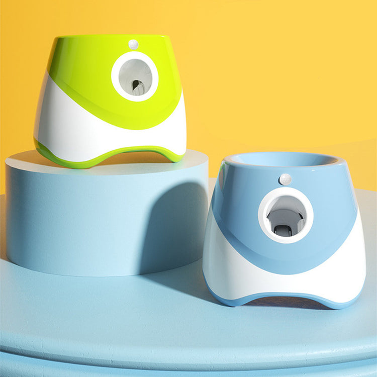 Lanzador automático de pelotas de tenis para perros en azul y verde, expuesto sobre un podio con fondo amarillo intenso.