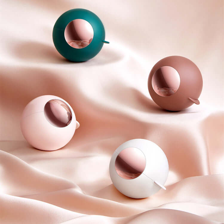 Four ball-shaped reusable lint rollers in various colors displayed on soft fabric surface.